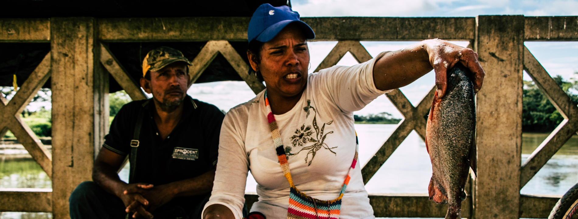 Un hombre y una mujer trabajan con pescado junto a un rio